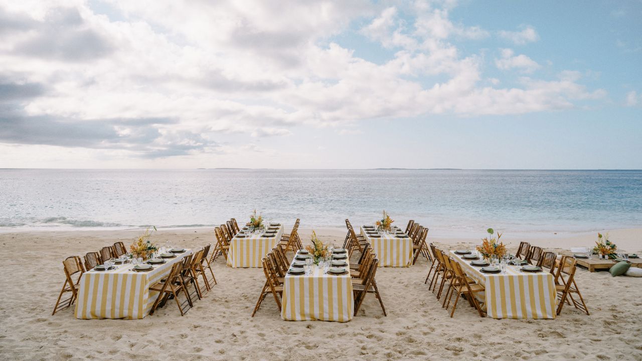 photo of reception tables and chairs at the beach right beside the ocean