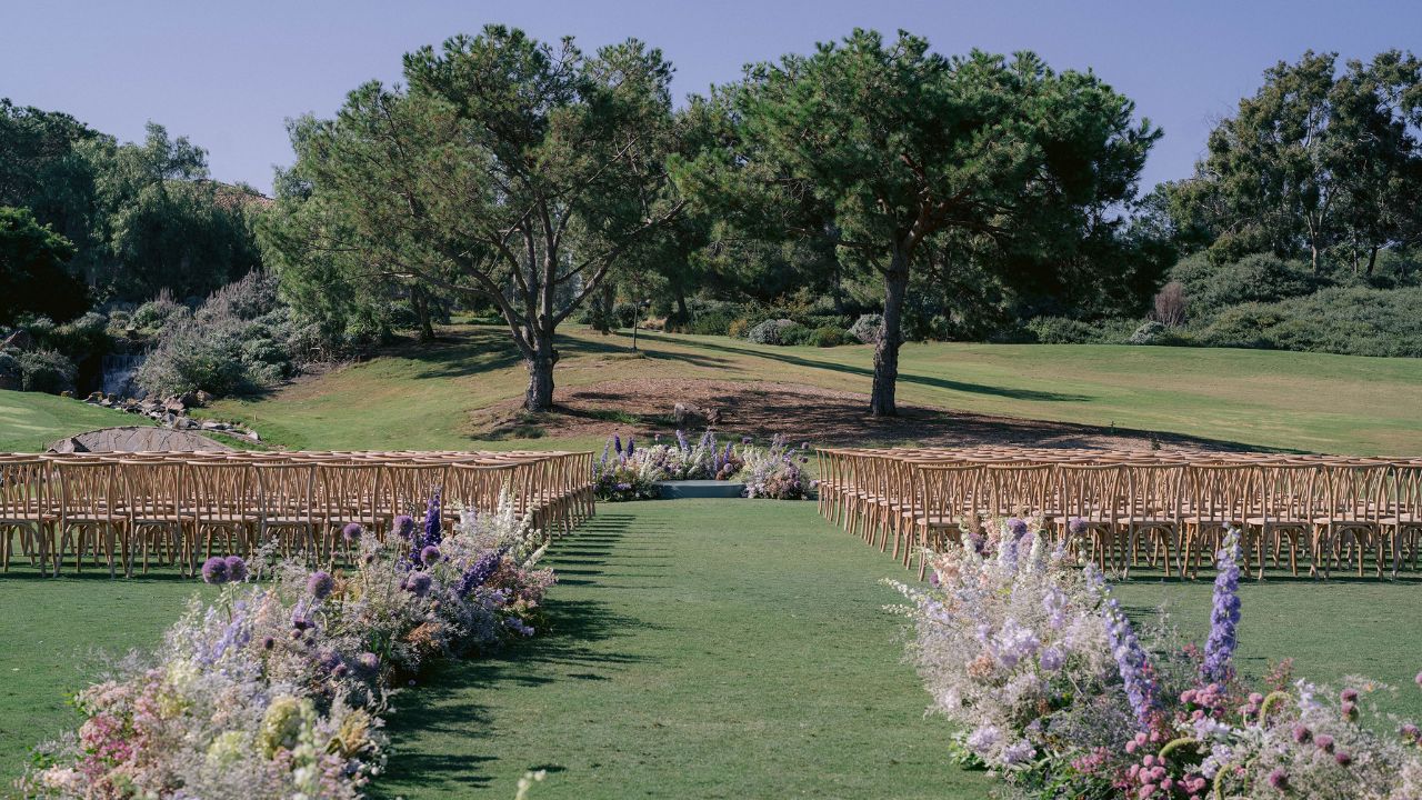 photo of wedding ceremony venue with flowers lining the aisle and facing trees