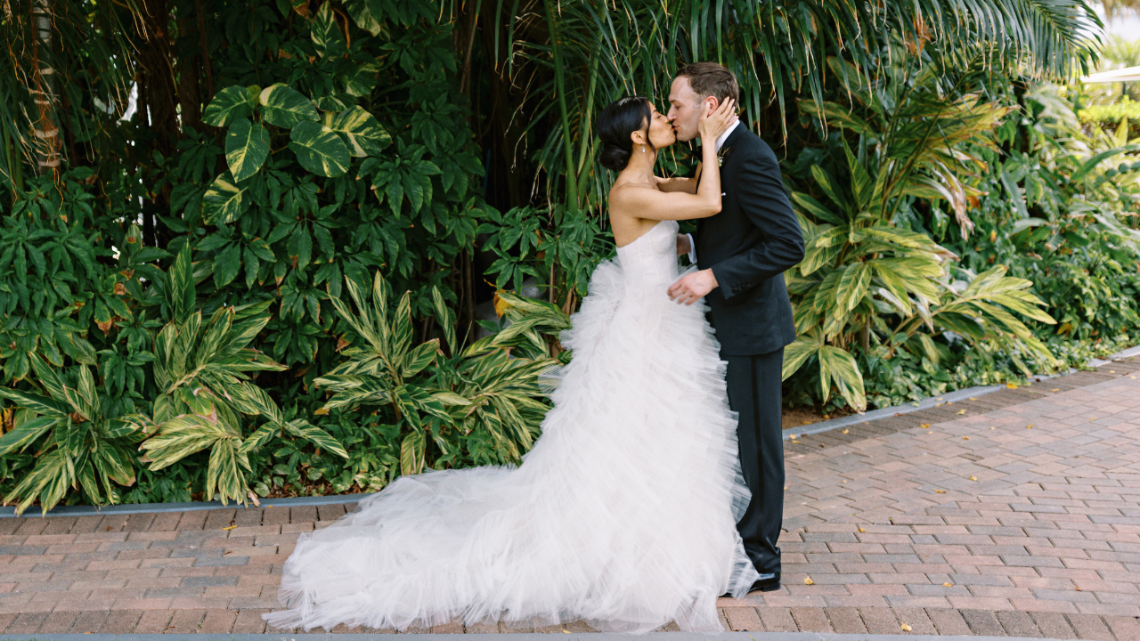 photo of couple kissing along a sidewalk on wedding day