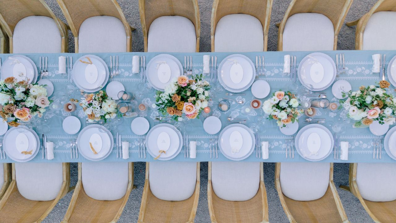 photo of blue wedding reception table with pink and cream floral arrangements