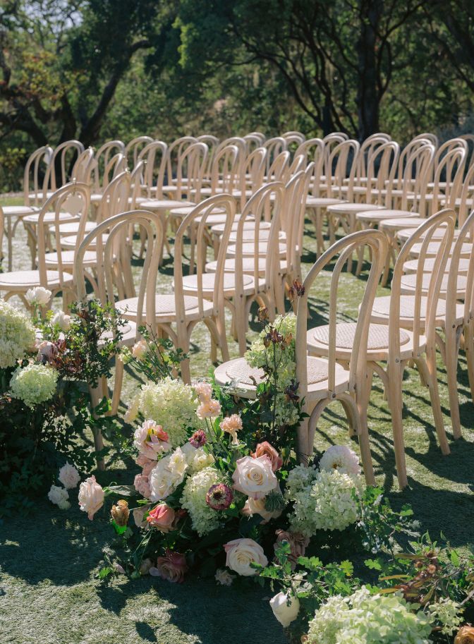 photo of ceremony wooden chairs with flowers lining the aisle