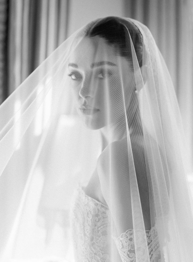 black and white photo of woman on wedding day with veil covering her face